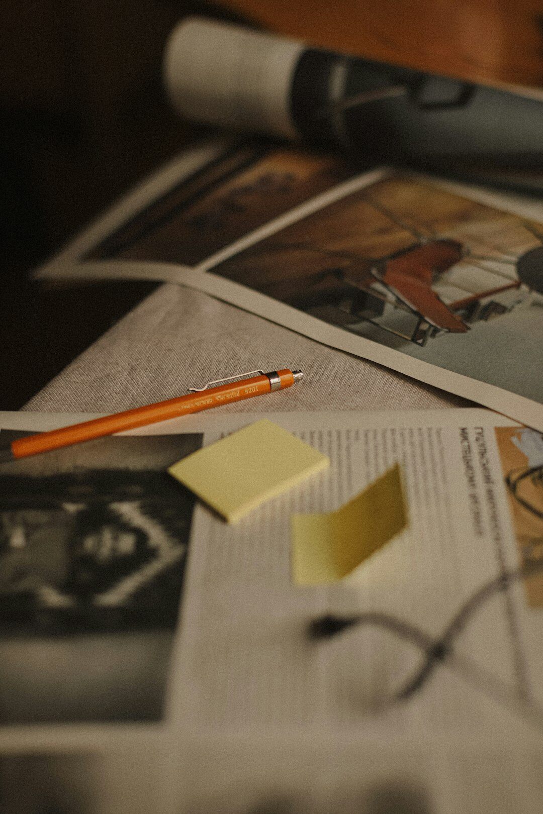 Journalist annotating printed photographs and sketching a page layout on a desk